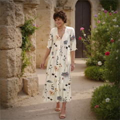 Woman in a floral dress standing in a garden with stone architecture
