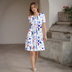 Woman wearing a floral dress standing in an outdoor setting with concrete steps and plants.