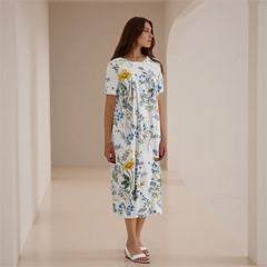 Woman wearing a floral dress standing in a softly lit room.