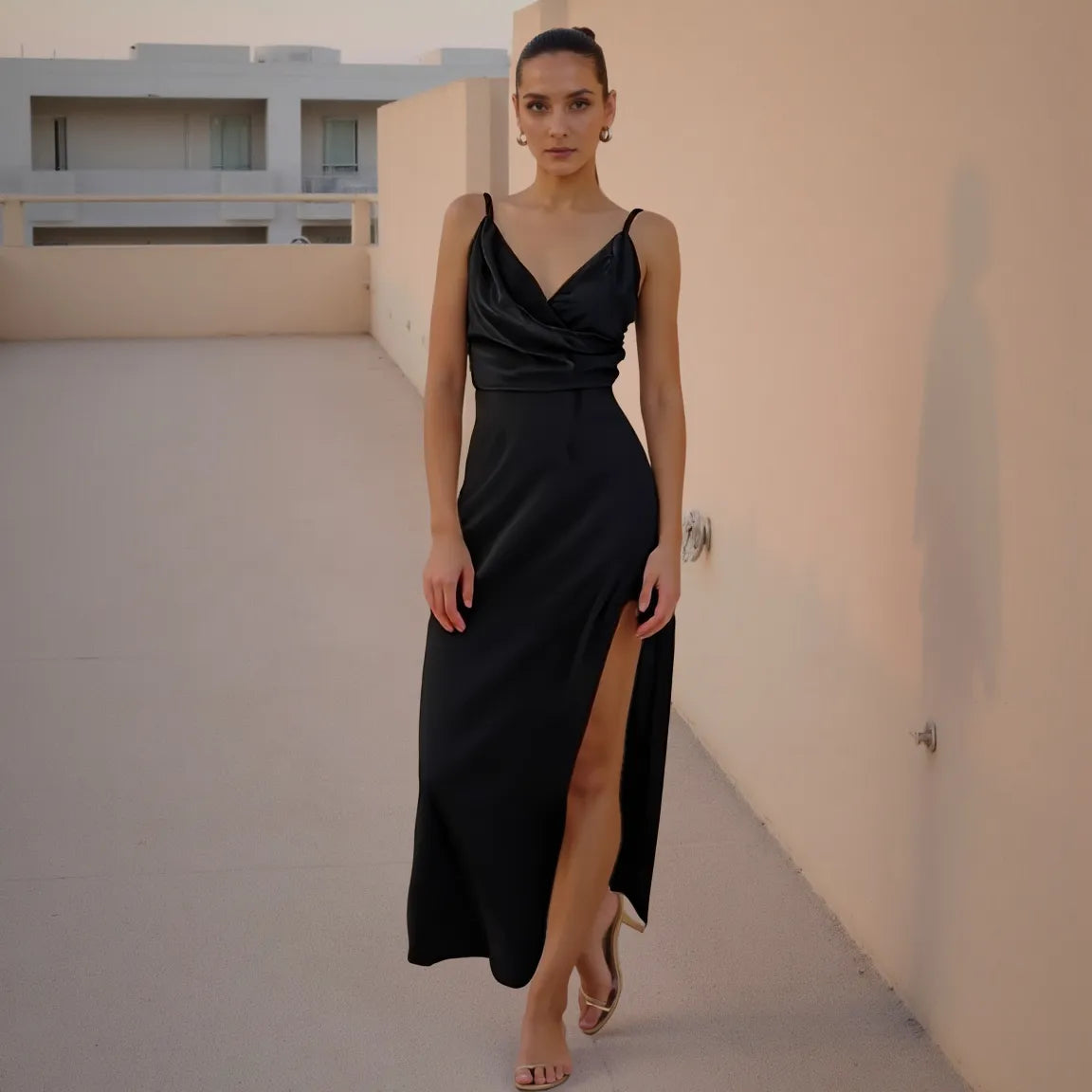 Woman in a black dress standing on a rooftop with minimalistic architecture in the background
