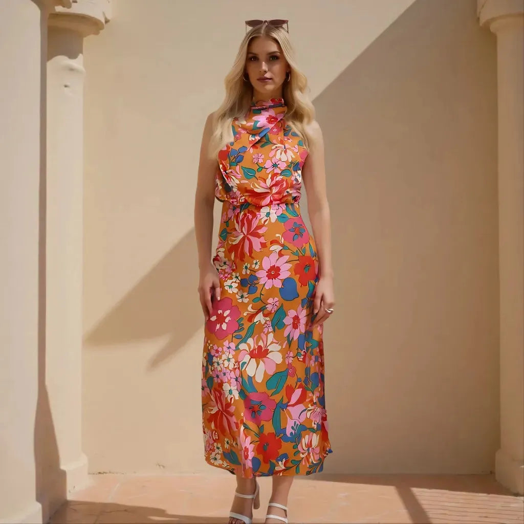 Woman wearing a colorful floral dress standing against a beige wall.