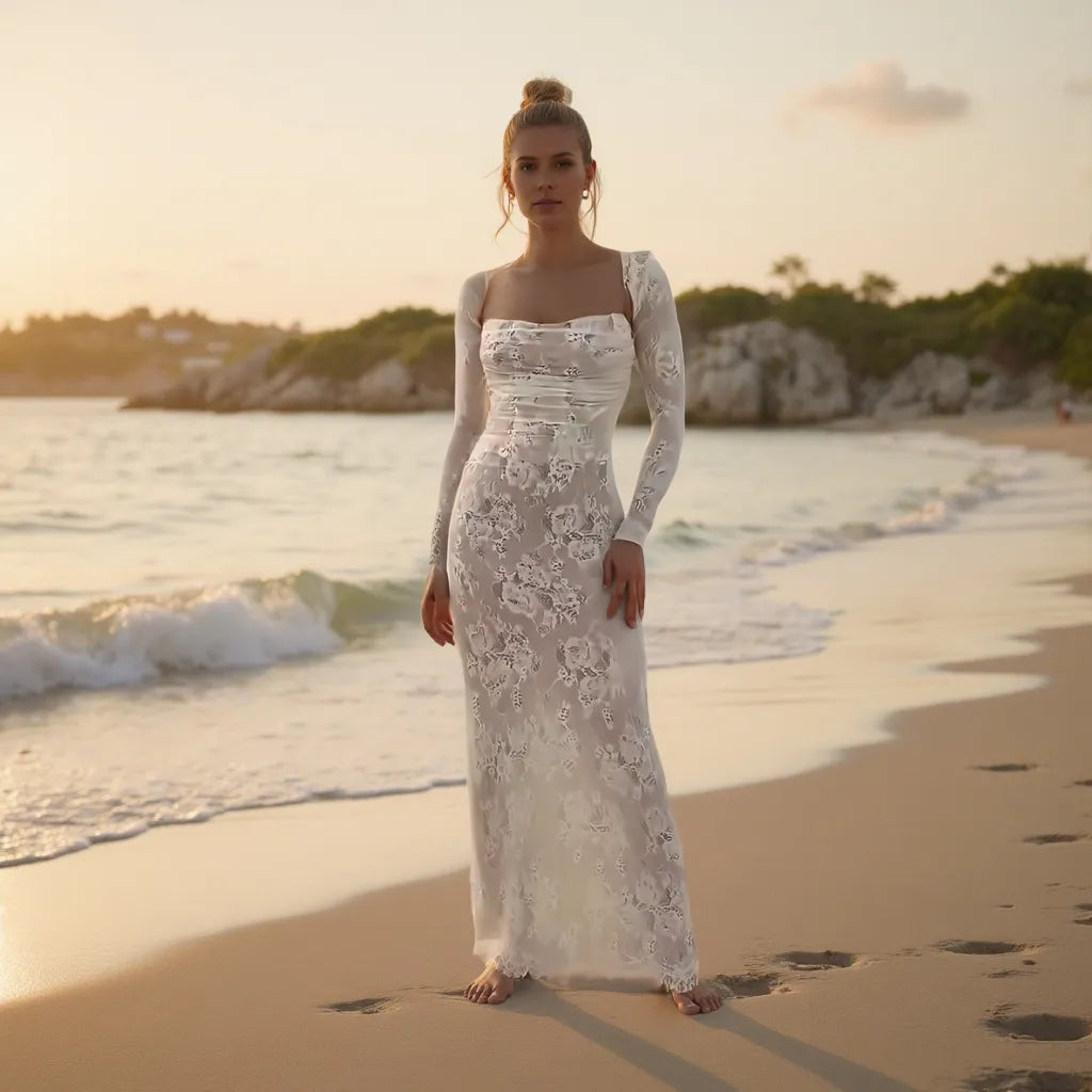 Woman in a white lace dress standing on a beach at sunset