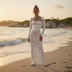 Woman in a white lace dress standing on a beach at sunset