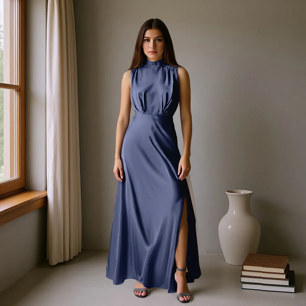 Woman in a long blue dress standing in a room with a window and decorative items.