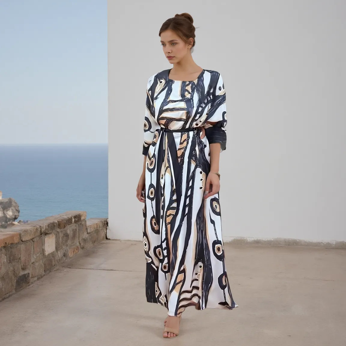 Woman wearing a patterned dress standing on a stone pathway with ocean view