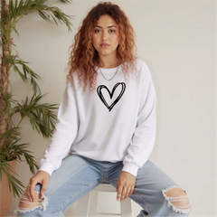 Person wearing a white sweatshirt with a black heart design and ripped jeans sitting indoors.