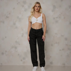 Woman wearing a white top and black pants against a neutral background
