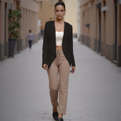 Woman walking down a street wearing a black blazer and beige pants.