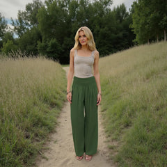 Woman standing on a dirt path in a natural setting with trees and grass.