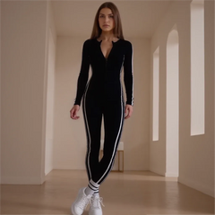 Woman wearing a black and white outfit in a minimalistic room with arched doorways.