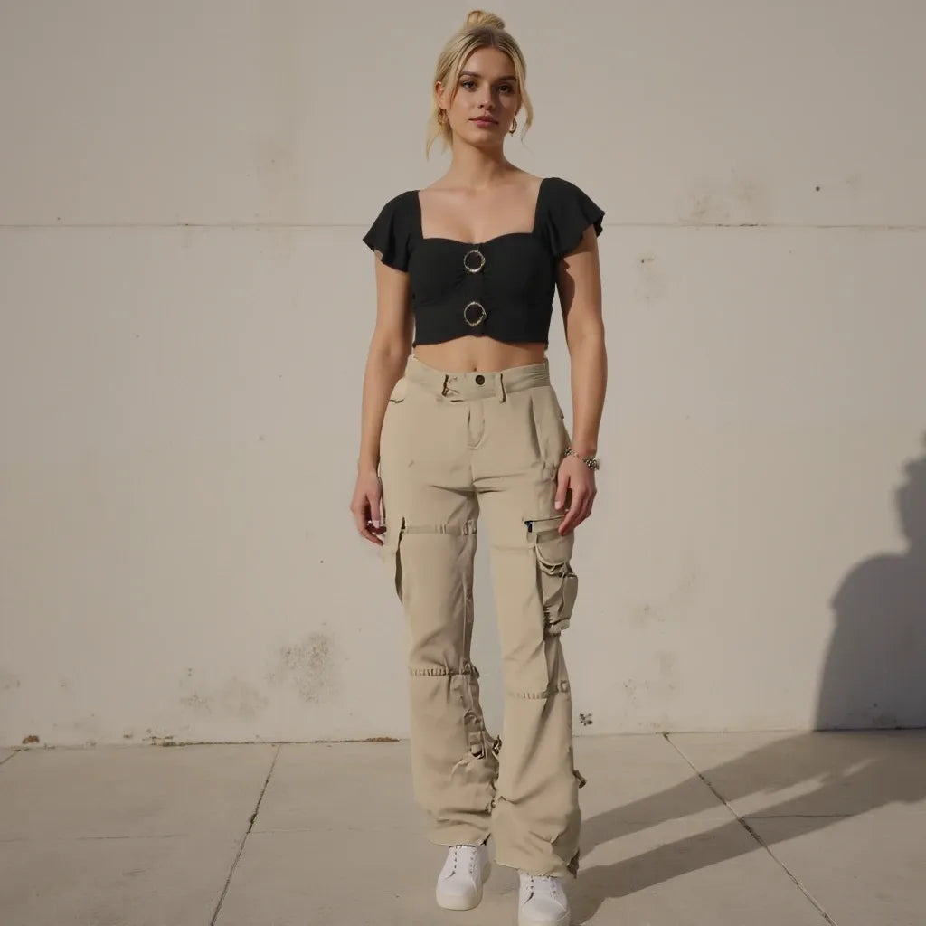 Woman wearing a black crop top and beige cargo pants against a plain wall.