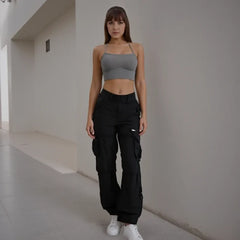 Woman wearing a gray crop top and black cargo pants in an indoor setting