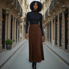 Woman in a black top and brown skirt standing on a city street.