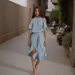 Woman in a light blue dress walking down a sunlit alleyway.