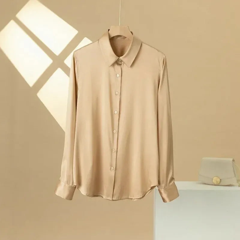 Beige shirt on a hanger against a beige wall with a light fixture.