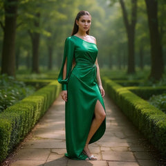 Woman in a green dress standing in a garden with manicured hedges and trees.