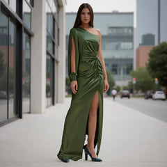 Woman in a green one-shoulder dress standing on a city street.