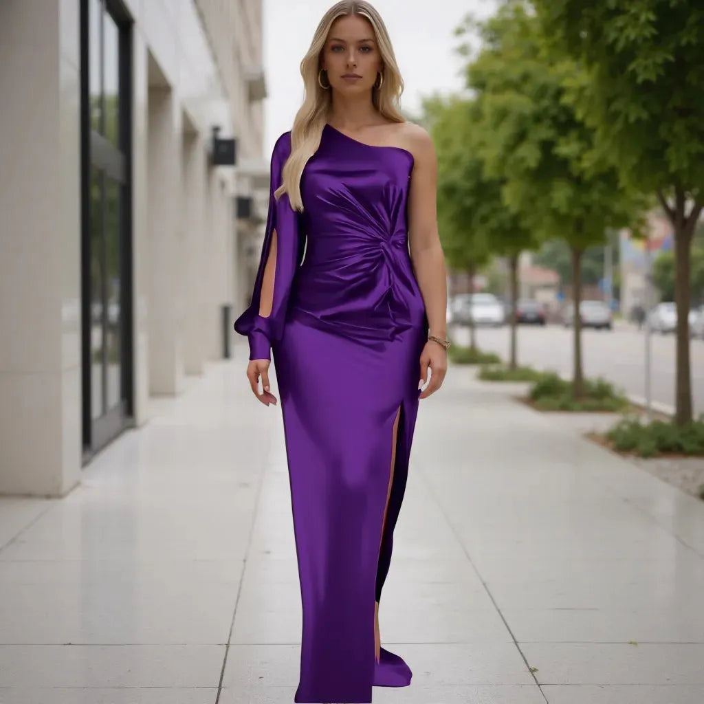 Woman in a purple one-shoulder dress standing on a sidewalk.