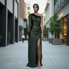 Woman in a green one-shoulder dress standing on a city street.