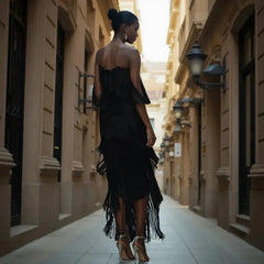 Woman in a black fringe dress walking down a narrow street with classical architecture.