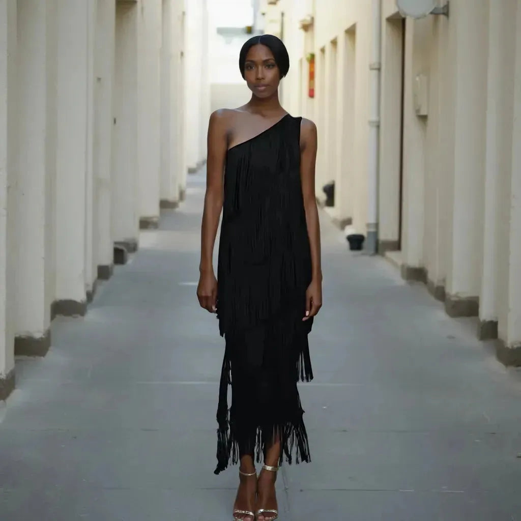 Woman wearing a black one-shoulder dress standing in a narrow alleyway.