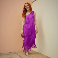 Woman wearing a purple fringe dress against a plain wall.