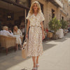 Woman in a leopard print dress walking on a city street.