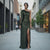 Woman in a green one-shoulder dress standing on a city street.