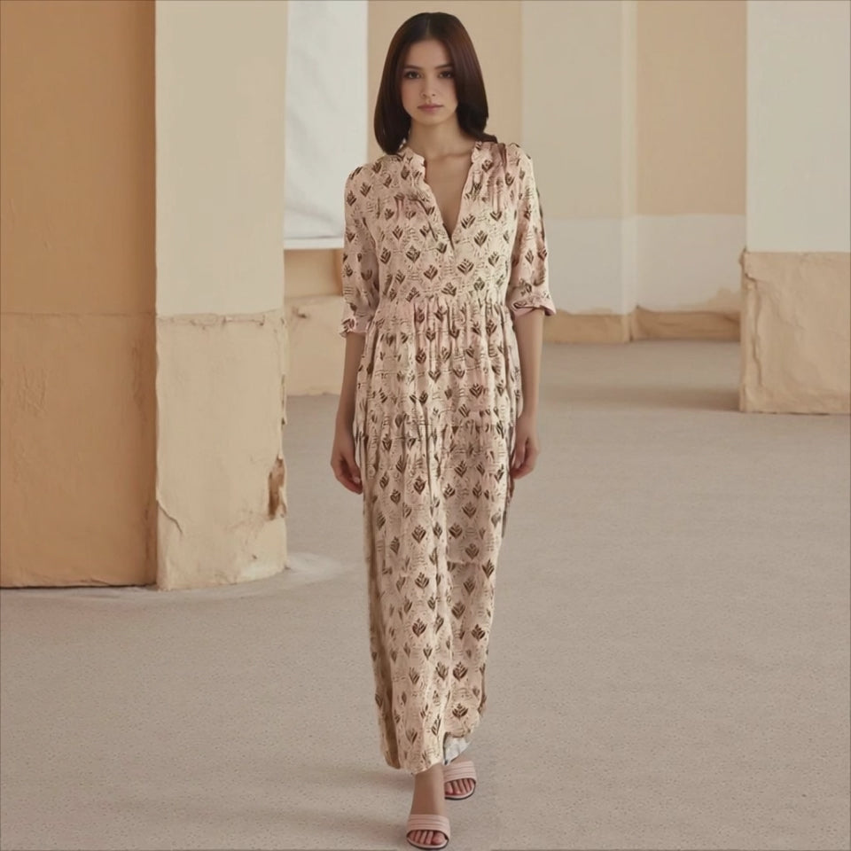 Woman wearing a patterned dress standing in a room with beige walls and carpet.