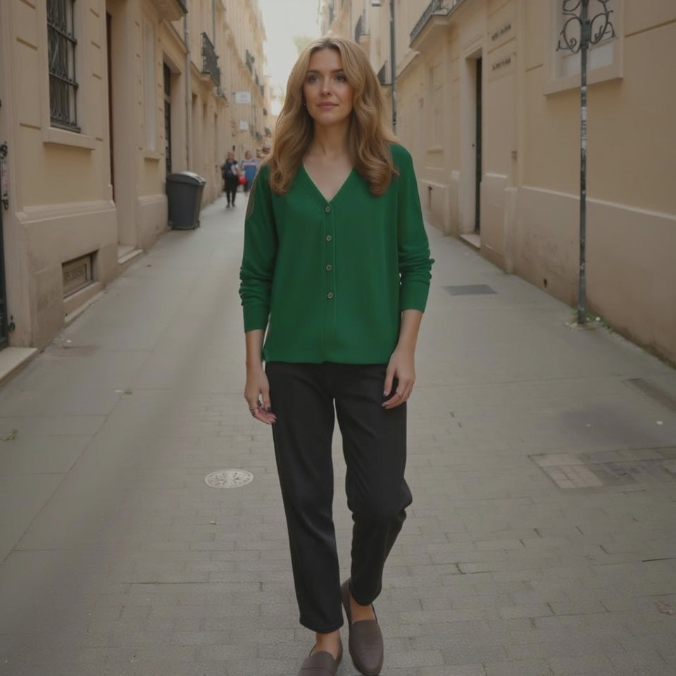 Woman in a green shirt and black pants walking down a narrow street.