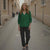 Woman in a green shirt and black pants walking down a narrow street.