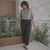Woman standing on a balcony with plants and a stone wall background