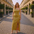 Woman in a yellow dress standing on a cobbled street with classical architecture.