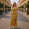 Woman in a yellow dress standing on a cobbled street with classical architecture.
