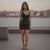 Woman in a black dress standing on a rooftop with cityscape in the background