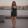 Woman in a black dress standing on a rooftop with cityscape in the background