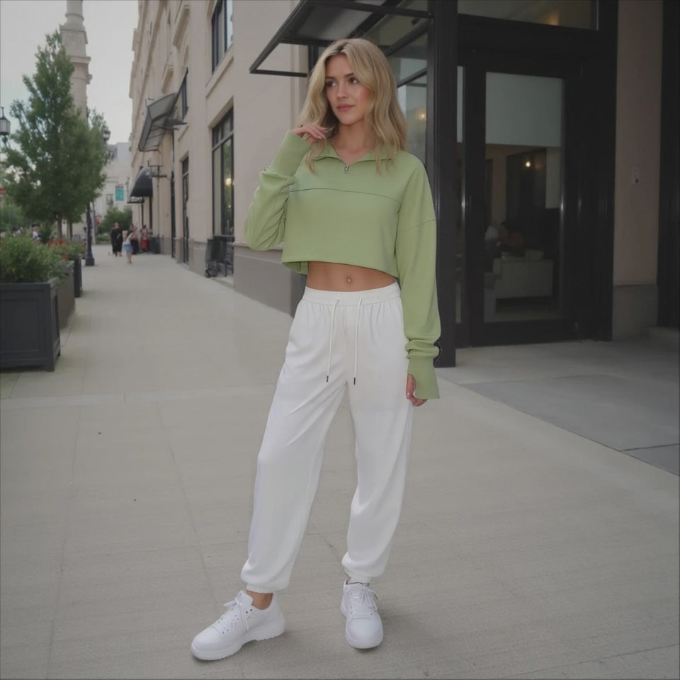 Woman in a green crop top and white pants standing on a city street.