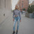 Woman in a textured sweater and ripped jeans standing on a city street.