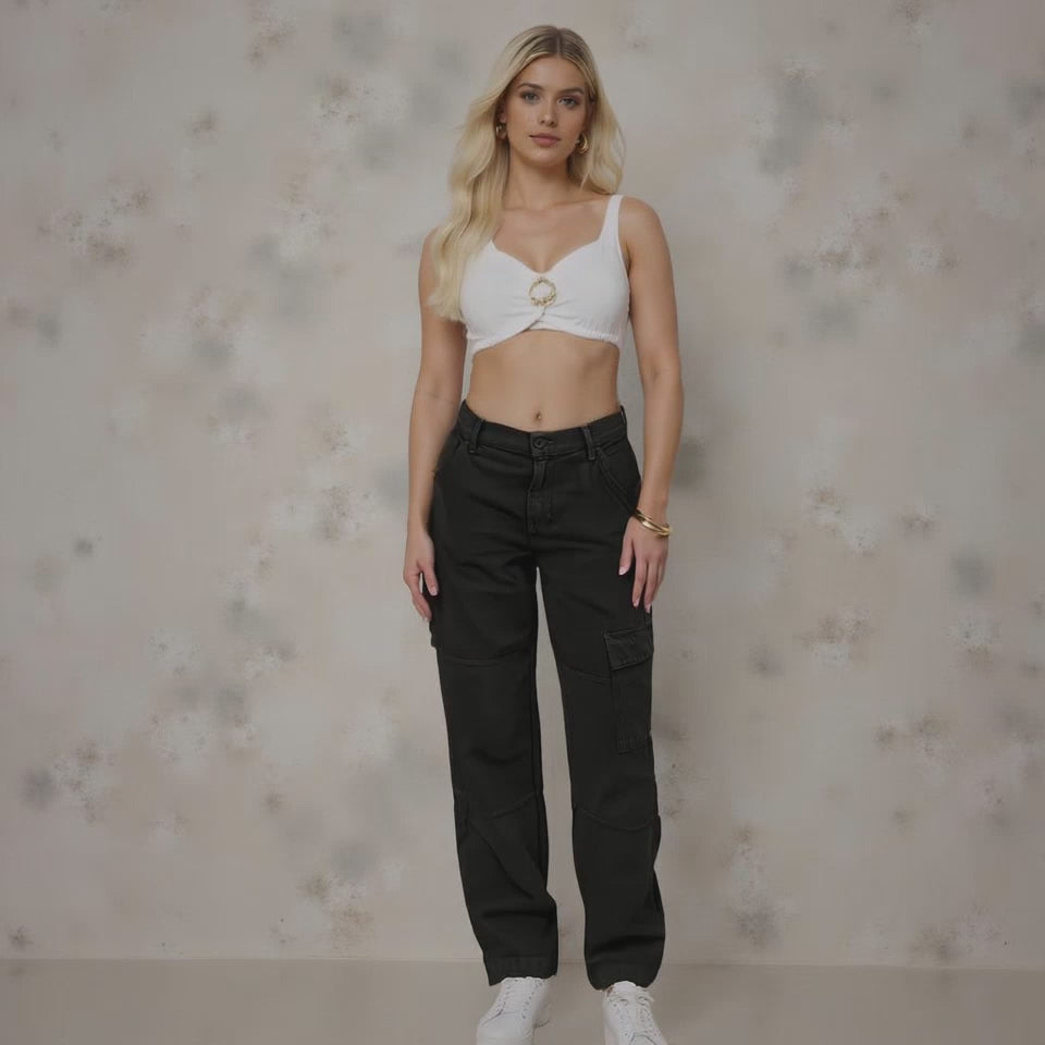 Woman wearing a white top and black pants against a neutral background