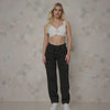 Woman wearing a white top and black pants against a neutral background