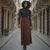 Woman in a black top and brown skirt standing on a city street.