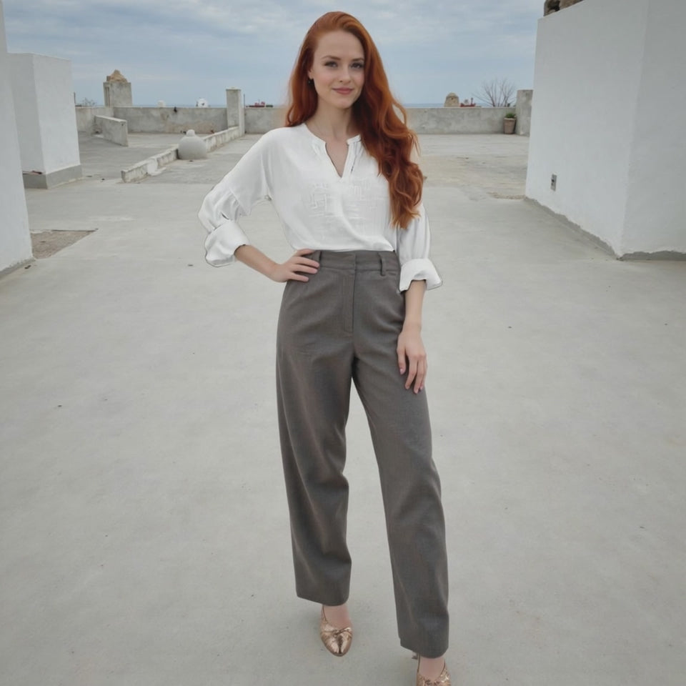 Woman in white blouse and gray pants standing on a rooftop.