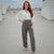 Woman in white blouse and gray pants standing on a rooftop.