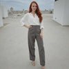 Woman in white blouse and gray pants standing on a rooftop.