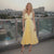 Woman in a yellow dress standing on a rooftop with a cityscape background