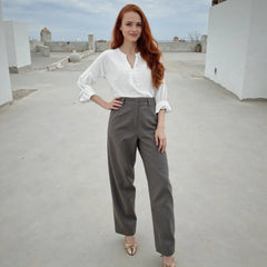 Woman in white blouse and gray pants standing on a rooftop.