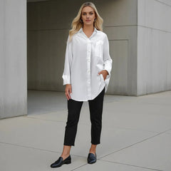 Woman wearing a white shirt and black pants standing against a neutral background