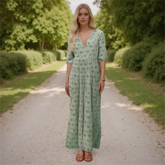 Woman in a green dress standing on a path with trees in the background