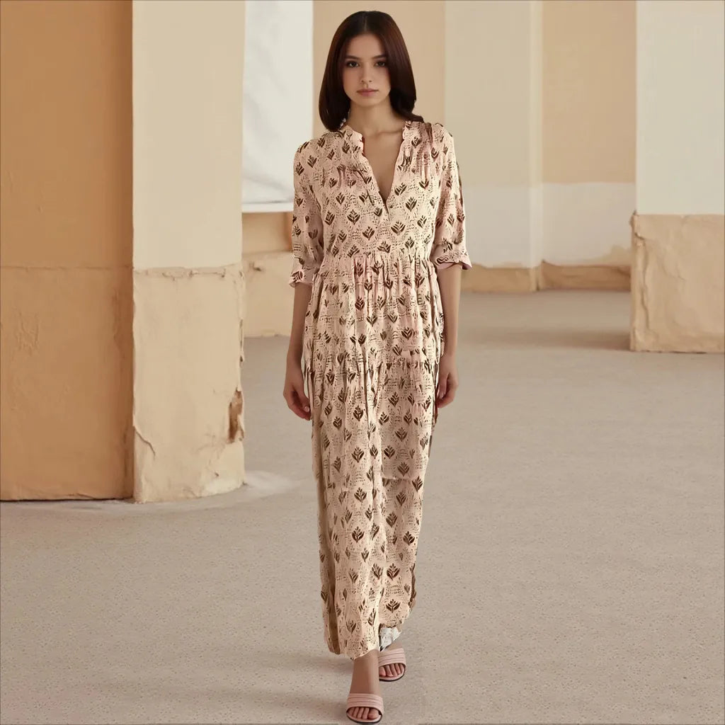 Woman wearing a patterned dress standing in a room with beige walls and carpet.