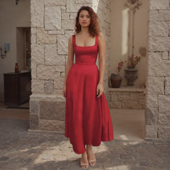 Woman in a red dress standing in front of a stone wall.